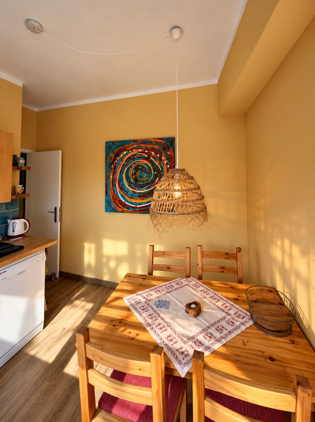 Essplatz mit Holztisch und Rattanlampe vor gelber Wand