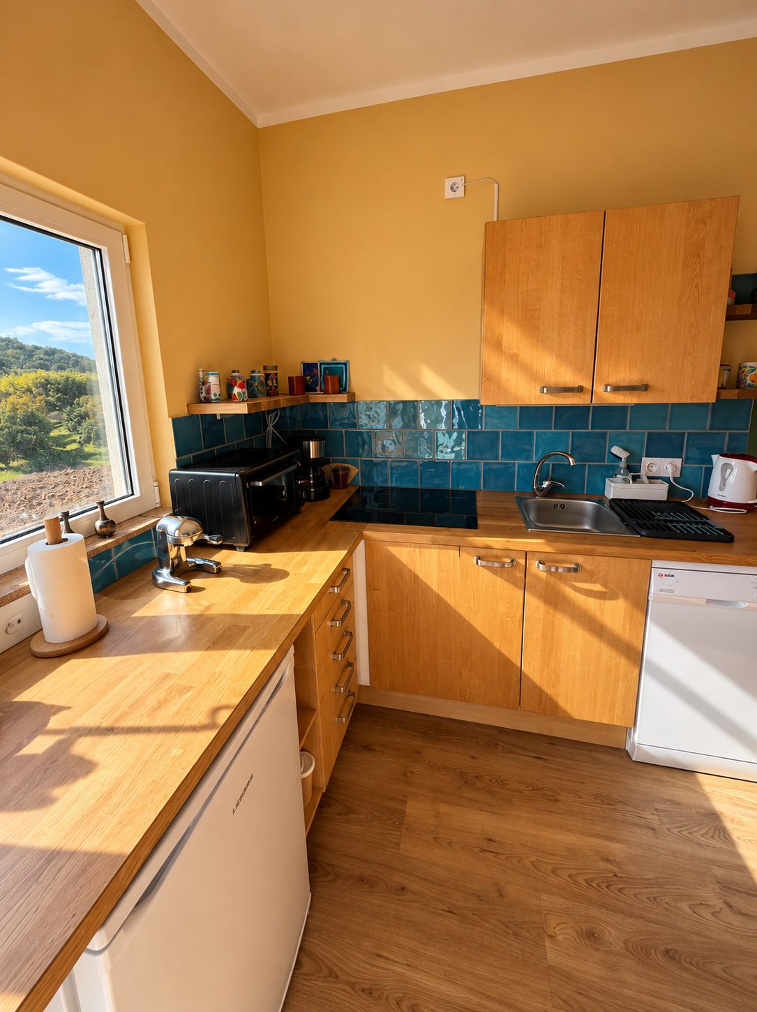 Küche mit Holzfronten, blauen Fliesen und Fenster