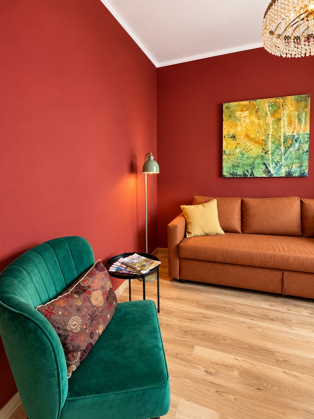 Wohnzimmer mit roter Wand, Ledersofa und grünem Samtsessel